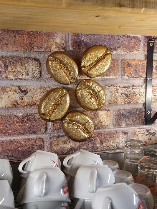 gouden koffieboon sculpturen boven koffieapparaat 