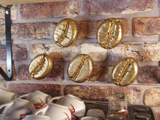 gouden koffieboon sculpturen boven koffieapparaat 